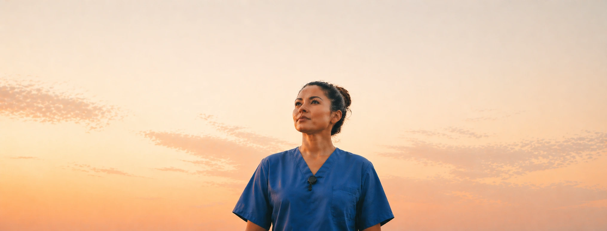 A nurse looking up at a warm sunset sky